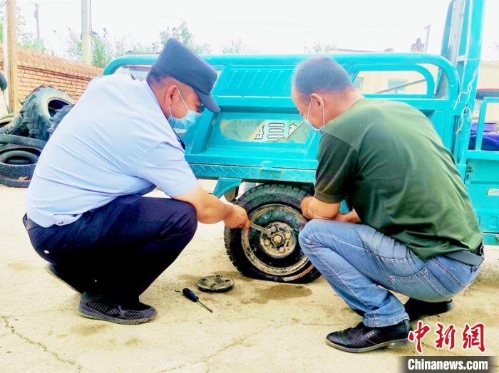 賽旦與民警共同維修三輪摩托車。　依力哈木江 攝
